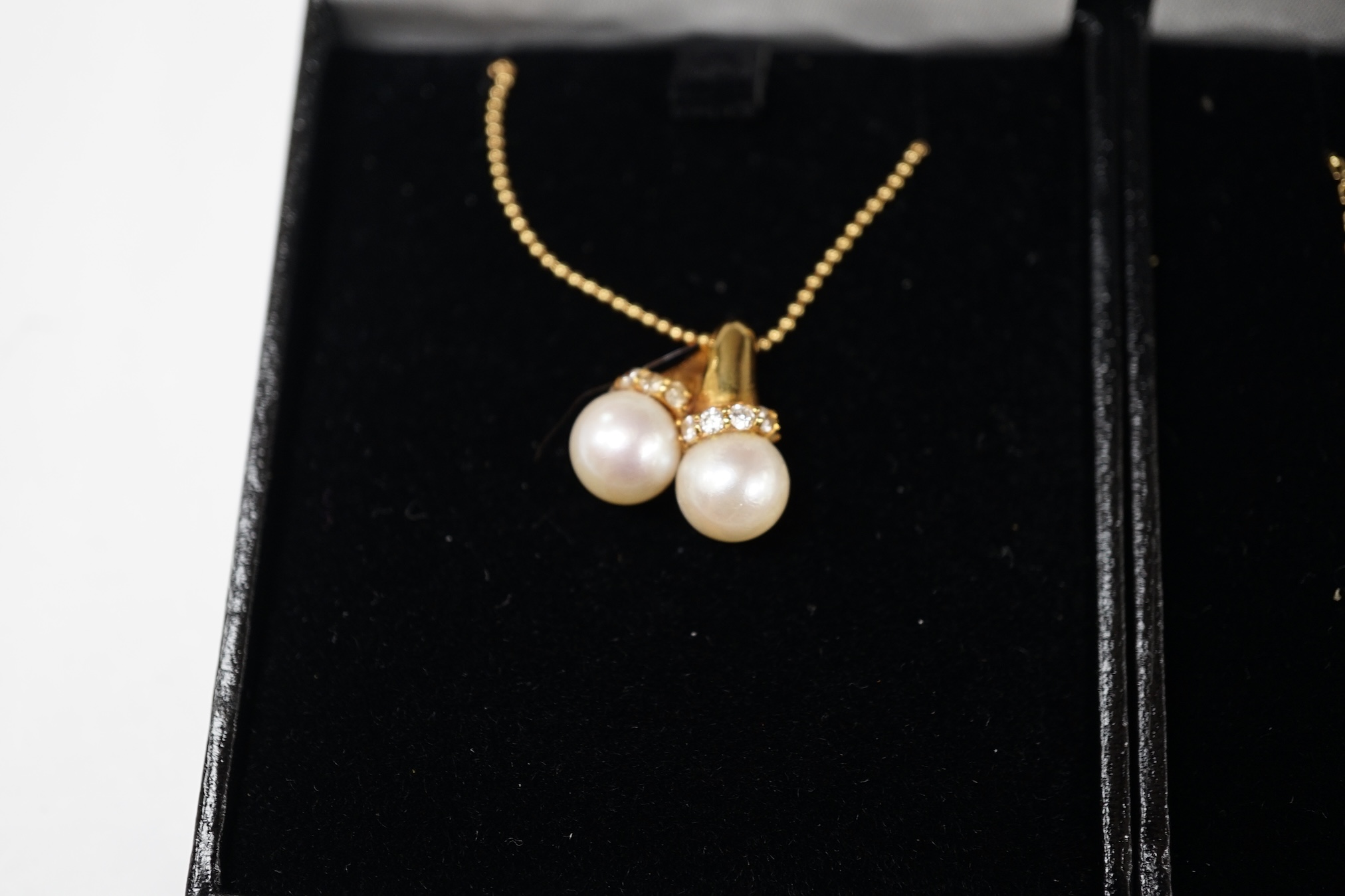 A modern 18k and two stone cultured pearl set pendant necklace, with diamond chip set collars, 42cm, gross weight 5.9 grams, together with a 14l and five stone cultured pearl set necklace, 35cm, gross weight 3 grams. Con